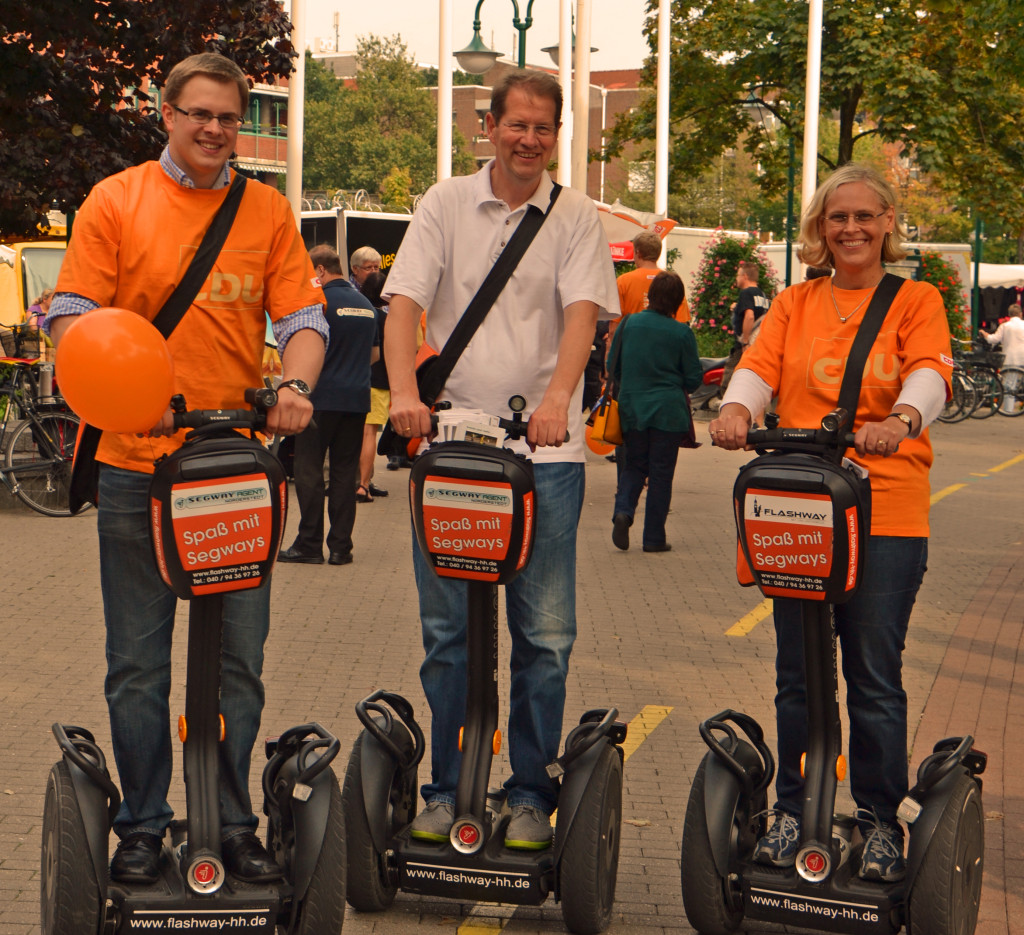 Ole Plambeck (Vorsitzender vom Kreisverband der Jungen Union), Gero Storjohann (Mitte) und Ruth Weidler (Vorsitzende vom CDU Ortsverband  Norderstedt) starten zur Flyer-Aktion auf Segways.