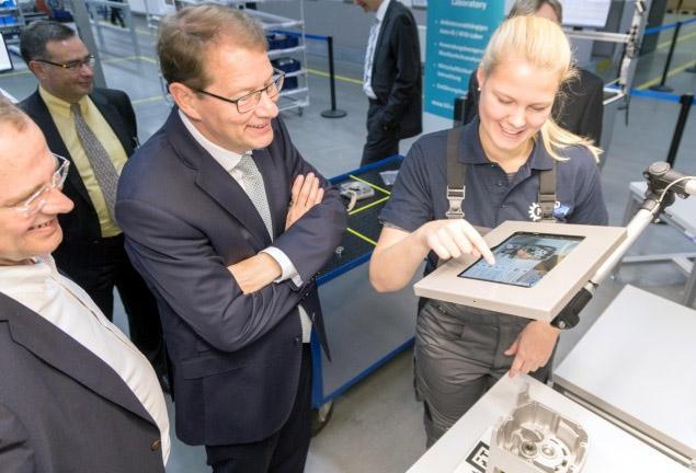 Besuch am Arbeitsplatz der Zukunft - Foto Bild 2: Augmented Reality: Sophia Greve, dual Studierende des Wirtschaftsingenieurwesens bei NORD, erklärt Gero Storjohann, MdB, und Landtagskandidat Christian Claussen die visuell gestützte Montage eines NORD-Getriebes am „Arbeitsplatz der Zukunft“